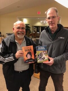 Two men holding books.